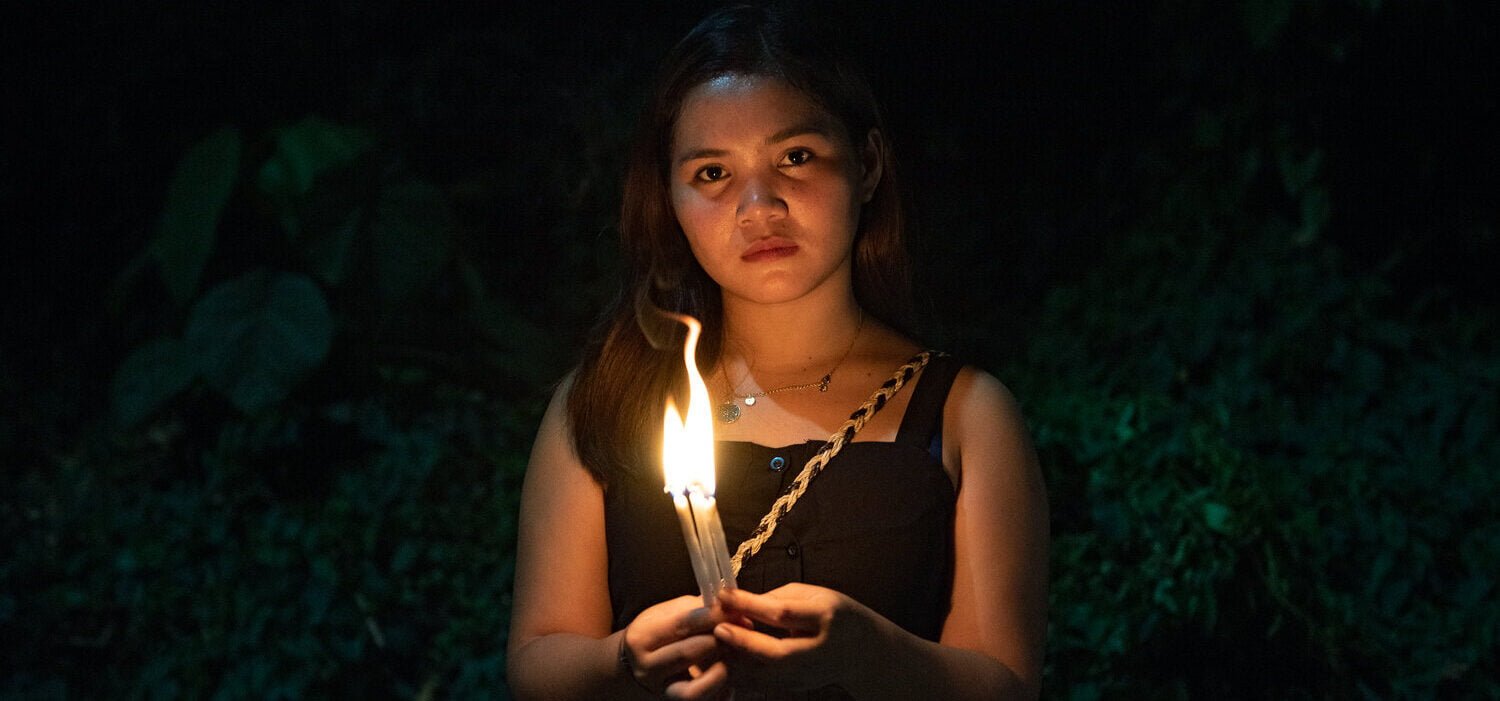 Photo of Marinel Sumook Ubaldo holding a candle in the dark.