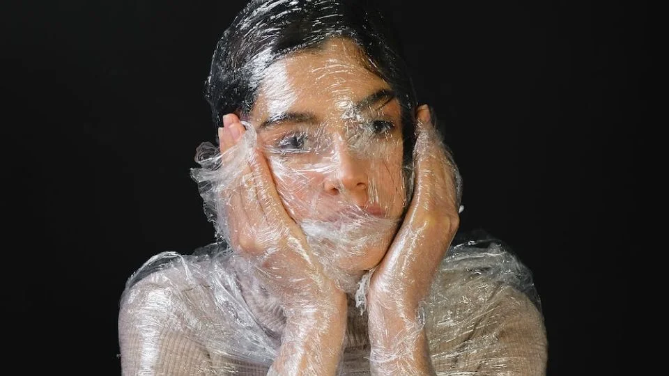 A woman wrapped in plastic with her mouth sealed shut