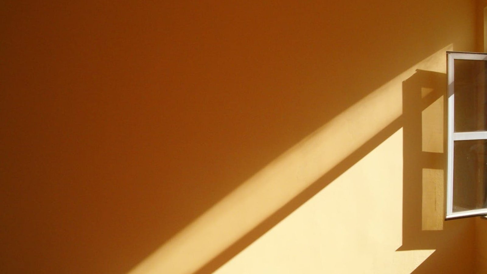 Light from a window falling on a terracotta colored wall showing minimalism
